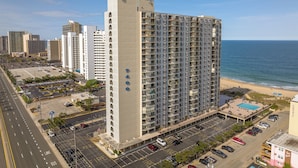 A high-rise hotel with multiple floors, a parking lot, and a beach view. - 2 Bedroom Ocean View Condo with Outdoor Pool! (Ocean City)
