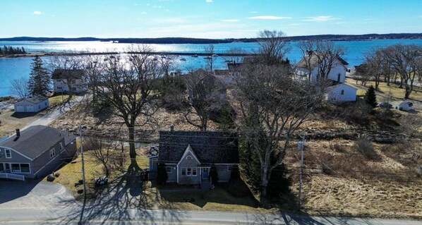 A residential area with houses near a body of water, a bridge in the background, and a clear sky.