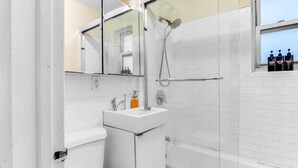 A modern bathroom with a white sink, mirror, and shower. - Amazing Columbus Circle & Central Park 3-Bedroom by ~ Queen Beds ~By Metro ~ W/D (New York)
