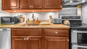 A kitchen with wooden cabinets, stainless steel appliances, a microwave, toaster, and a kettle. - Amazing Columbus Circle & Central Park 3-Bedroom by ~ Queen Beds ~By Metro ~ W/D (New York)