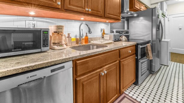 A modern kitchen with wooden cabinets, a Bosch dishwasher, a microwave, a coffee maker, a sink, and a refrigerator. - Amazing Columbus Circle & Central Park 3-Bedroom by ~ Queen Beds ~By Metro ~ W/D (New York)