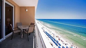 Un balcon donnant sur une plage, avec une table et des chaises.