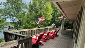 A wooden deck with red chairs and an American flag, overlooking a lake.