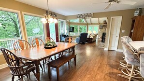 A spacious dining area with a wooden table and chairs, a bench, and a ceiling fan.