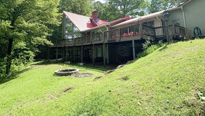 A two-story house with a red roof, a covered porch, and a small garden area.