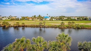 Vista de un lago con un campo de golf y edificios residenciales al fondo.