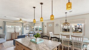 A spacious living area with a marble island, white dining set, and pendant lighting. - 5206 Hogg Heaven * 3 Min Walk to Beach (Kill Devil Hills)