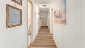A hallway with wooden flooring, white walls, and framed artwork. - 5206 Hogg Heaven * 3 Min Walk to Beach (Kill Devil Hills)