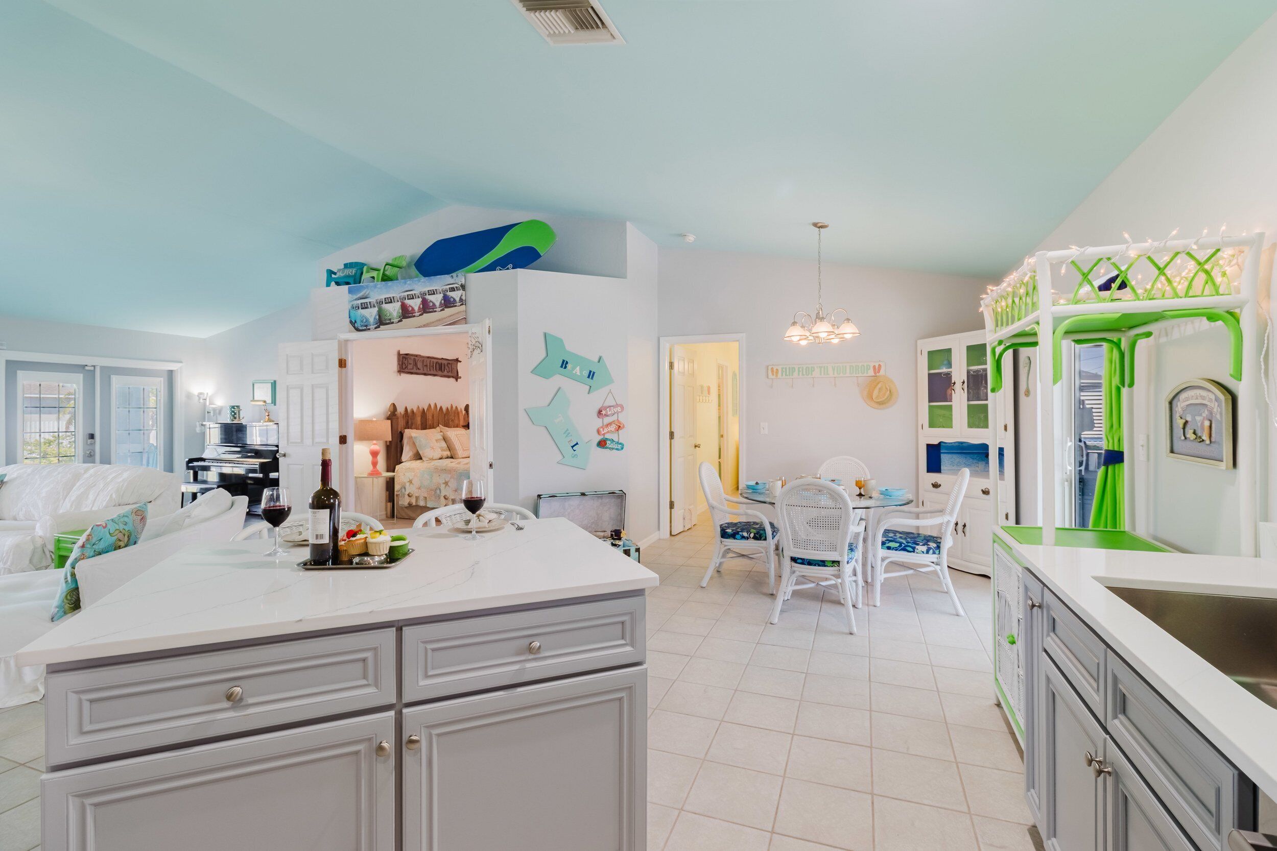 A spacious kitchen with a central island, white cabinets, and a dining area with white chairs.