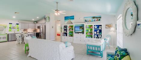 A spacious living area with a large bed, a dining table, and a kitchen in the background.