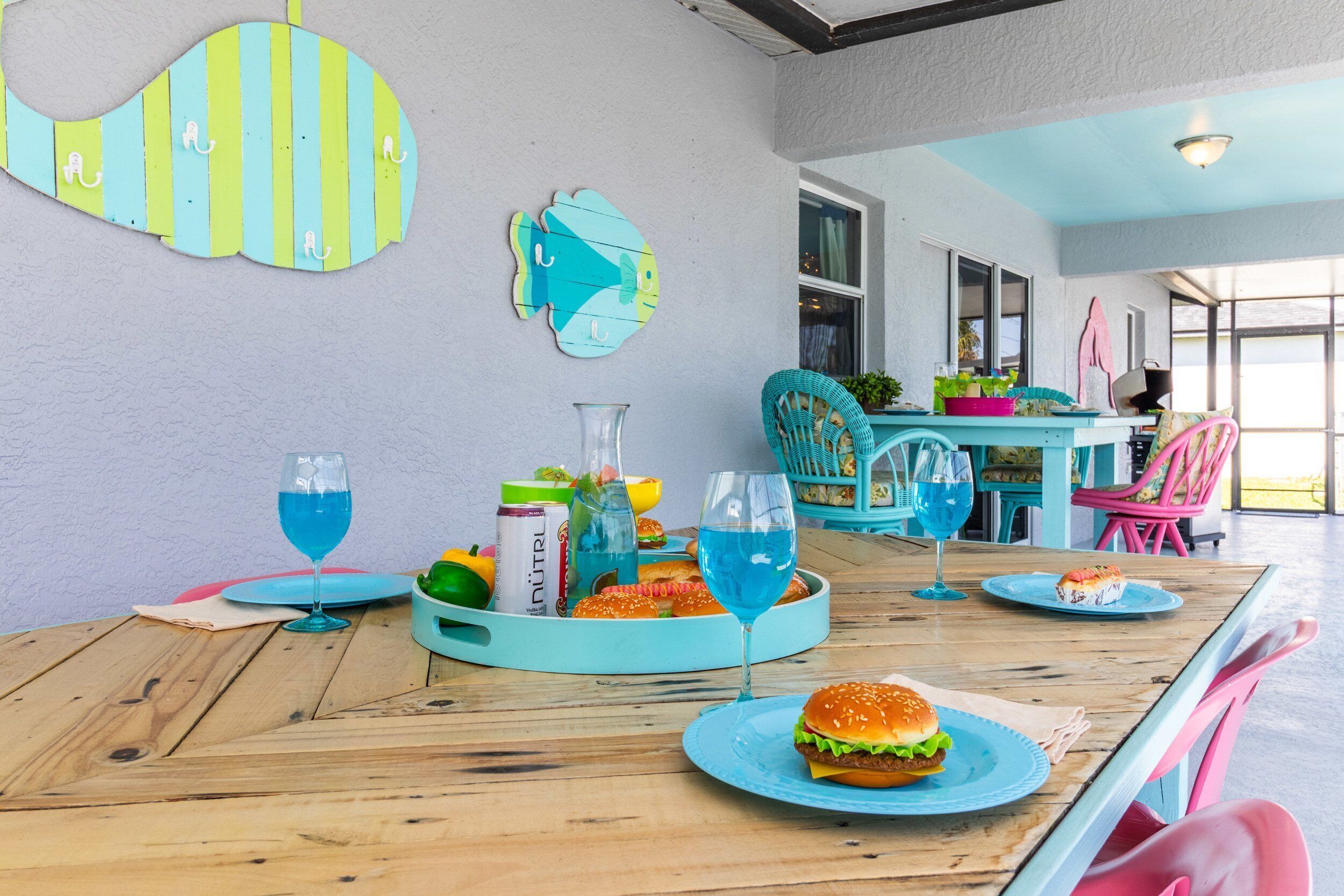 Ein Essbereich mit einem Holztisch, gedeckt für eine Mahlzeit, mit einem Burger und blauen Getränken.