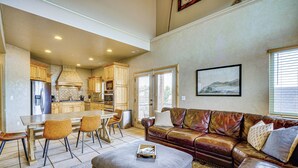 A spacious living room with a leather sofa, a dining table with chairs, and a kitchen in the background. - Hot Tub & Mtn-View Deck: Townhome in Eden (Eden)