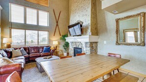 A spacious living area with a large wooden dining table, leather sofas, and a stone fireplace. - Hot Tub & Mtn-View Deck: Townhome in Eden (Eden)