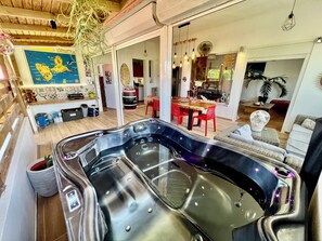 Ein modernes Wohnzimmer mit einer grossen Whirlwanne, Holzböden und einem Essbereich mit roten Stühlen.