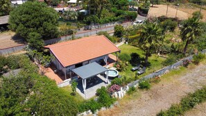 A house with a red-tiled roof, a patio with outdoor furniture, and a hot tub.
