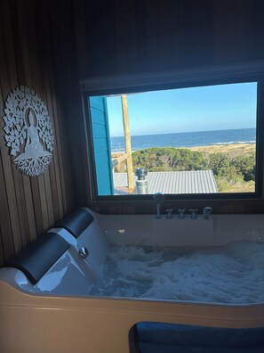 Une salle de bain dotée d’une grande fenêtre, d’une baignoire et d’un élément décoratif mural.
