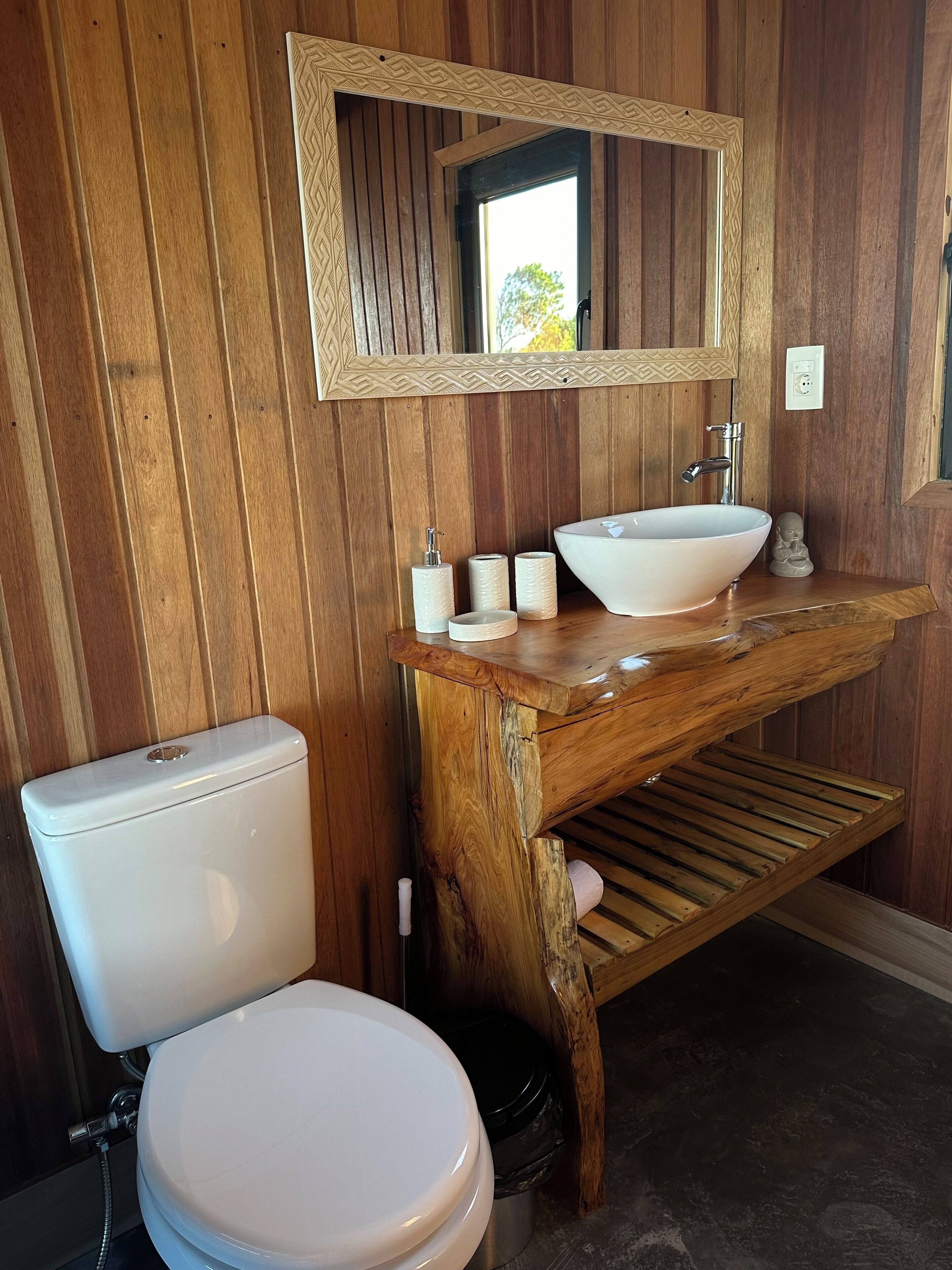A bathroom with a wooden vanity, a white sink, and a toilet.