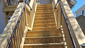 Una escalera de madera con barandillas de metal que lleva a una terraza.