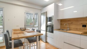 A modern kitchen with white cabinets, a wooden countertop, and a built-in oven.