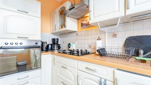 A kitchen with white cabinets, a stove, and a coffee maker.