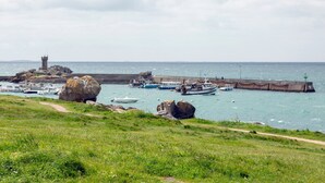 Un paysage côtier avec un phare, des bateaux et une côte rocheuse.