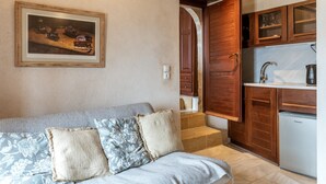 Ein gemütliches Zimmer mit einem Bett, einem gerahmten Gemälde, einer Küchenzeile mit Holzschränken und einem Kühlschrank.