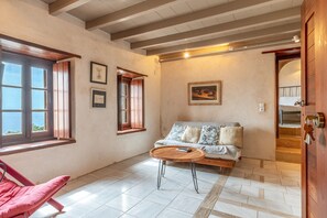 A room with a sofa, a round wooden table, a red chair, and a window with a view. - Guest House 'Goulas' with Sea View, Wi-Fi and Air Conditioning (Laconia)