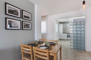 Ein Essbereich mit Holztisch und Stühlen, gerahmten Bildern an der Wand und einer Küche im Hintergrund.