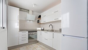 A modern kitchen with white cabinets, a built-in oven, a microwave, and a stainless steel sink. - Vacation 'El Pico' with Wi-Fi (La Santa)
