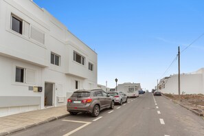 Eine Straße gesäumt von modernen Gebäuden, geparkten Autos und einem klaren Himmel.
