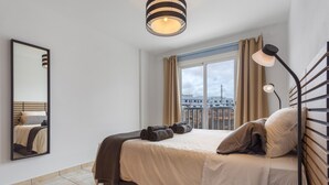 A bedroom with a bed, a mirror, a window with curtains, and a view of buildings outside. - Vacation 'El Pico' with Wi-Fi (La Santa)