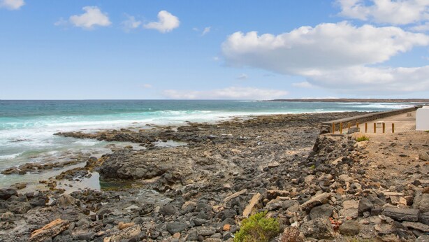 A rocky beach with a wooden walkway leading to a building. - Vacation 'El Pico' with Wi-Fi (La Santa)
