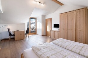 Une chambre à coucher avec un lit, un bureau, une télévision et des armoires en bois.