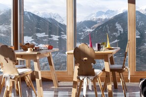 Una mesa de madera con sillas, una ventana con vistas a la montaña y una vela sobre la mesa.