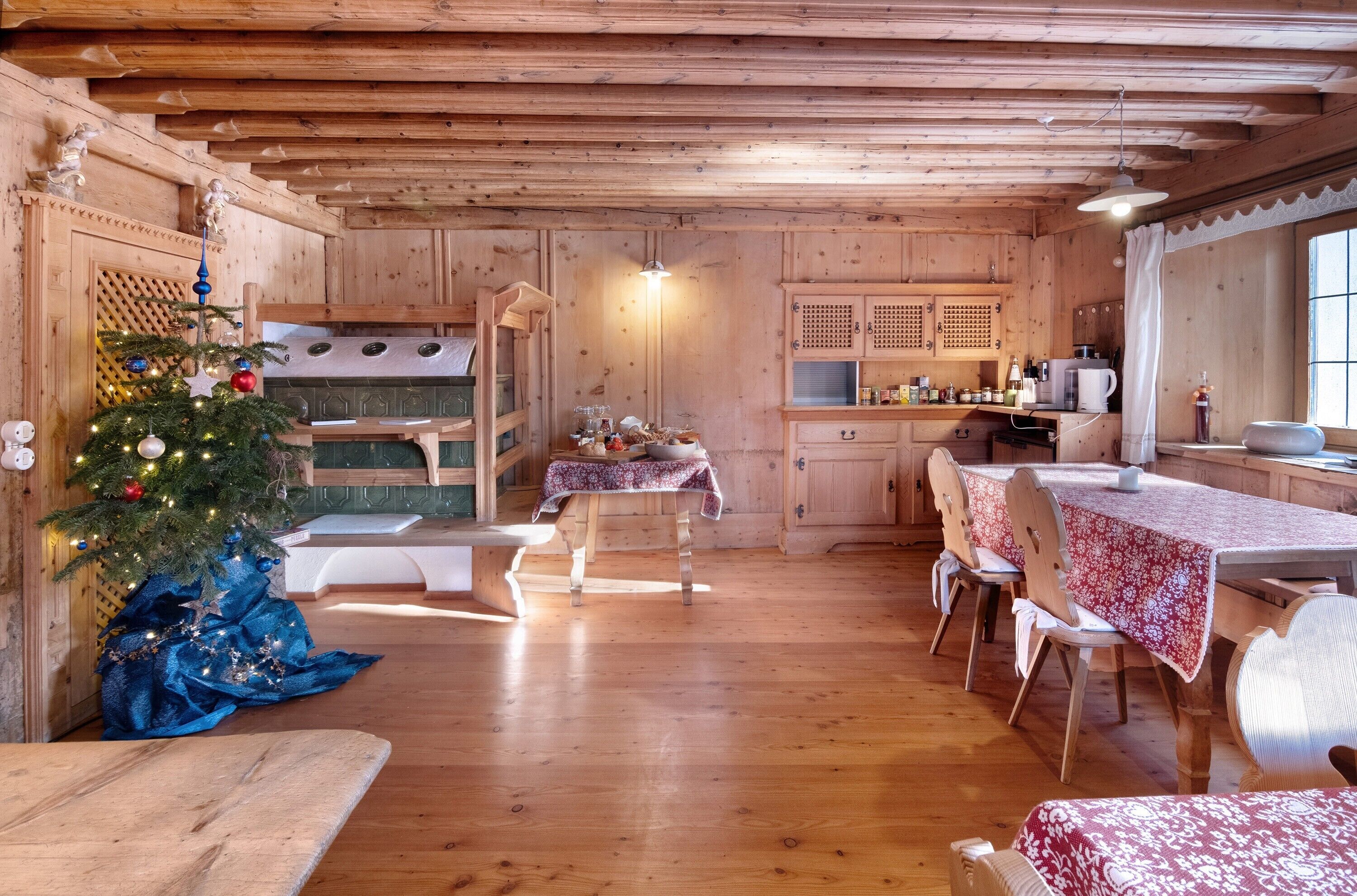 A wooden interior with a dining area, kitchen, and a decorated Christmas tree.