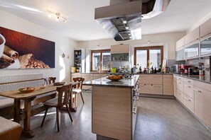 A modern kitchen with a central island, wooden dining table, and chairs.