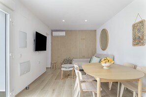 A modern living room with a wooden floor, a round dining table, and a sofa.