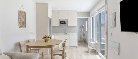 A modern kitchen with a microwave, wooden cabinets, and a dining area with a table and chairs.