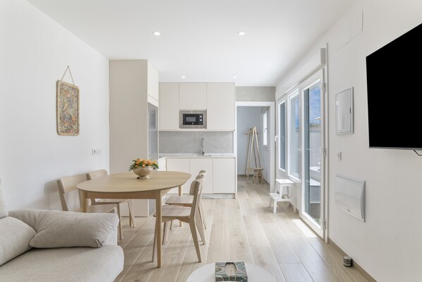 A modern kitchen with a microwave, wooden cabinets, and a dining area with a table and chairs.