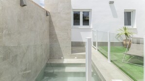 Un edificio moderno con piscina, barandilla de vidrio y una planta en maceta.