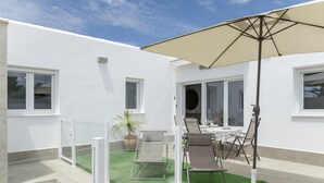 Un patio con mesa, sillas y una sombrilla.