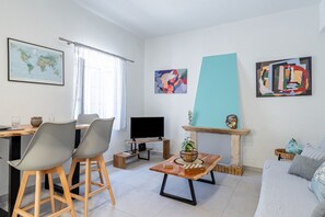 Un soggiorno moderno con zona pranzo, televisore a schermo piatto e opere d'arte astratte alle pareti.