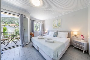 Una camera da letto con un letto grande, un comodino, una finestra con tende e un balcone con tavolo e sedie.