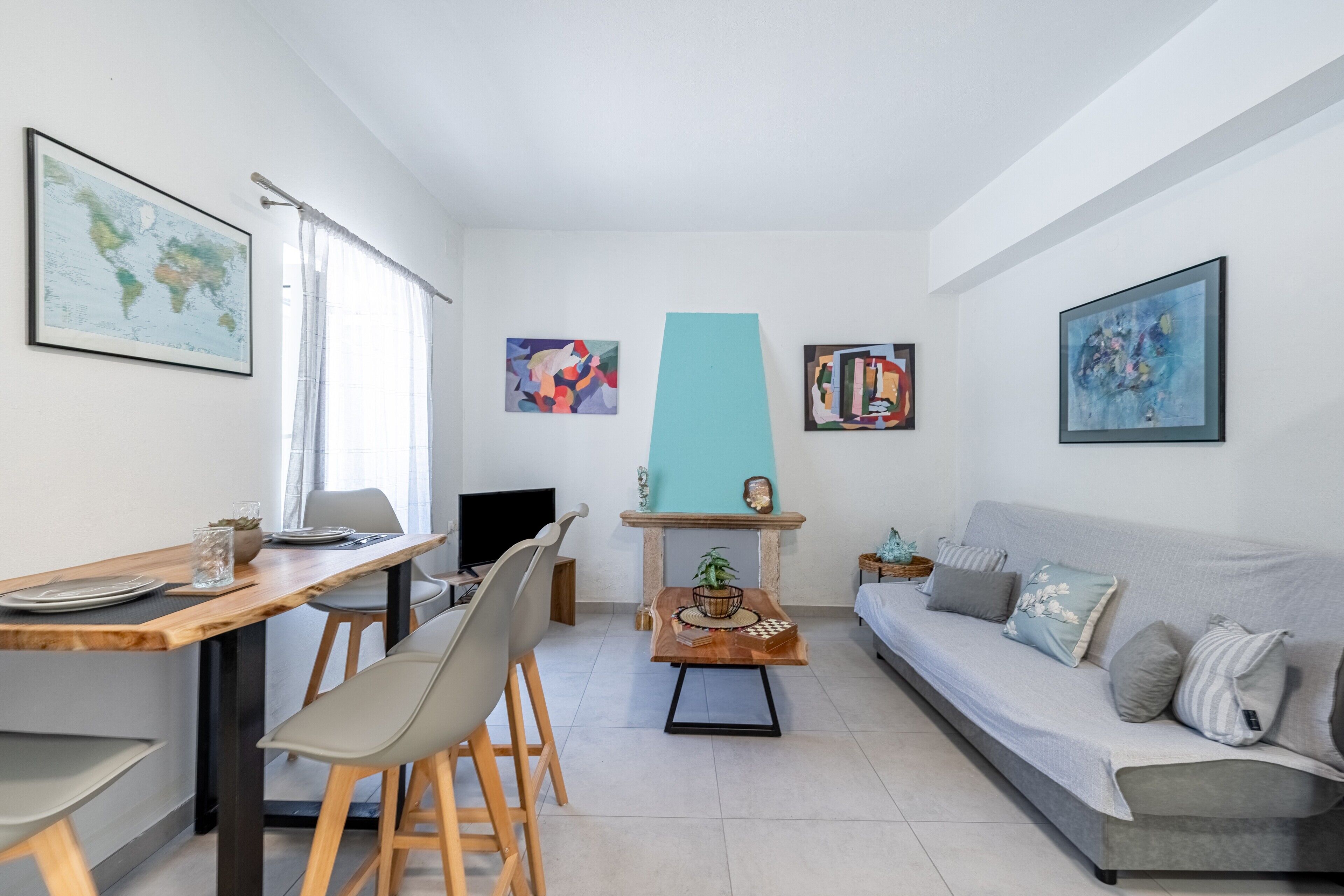 Una sala de estar moderna con comedor, sofá, mesa de centro y obras de arte en las paredes.