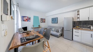 A modern kitchen with white cabinets, a grey sofa, and a dining table with chairs. - Holiday Home 'Di Babis' with Mountain View, Wi-Fi and Air Conditioning (Paxos)