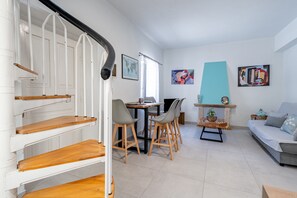 A modern living room with a staircase, a dining area, and a sofa.