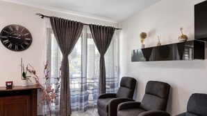Una habitación con un escritorio de madera, dos sillones, un reloj negro y una estantería con objetos decorativos.
