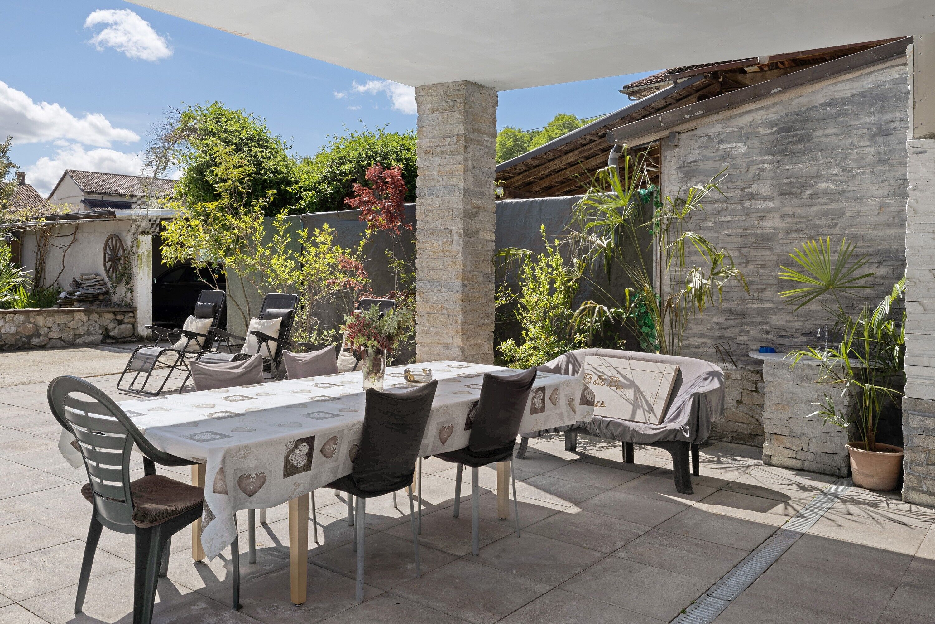 An outdoor patio with a table and chairs, stone walls, and potted plants.