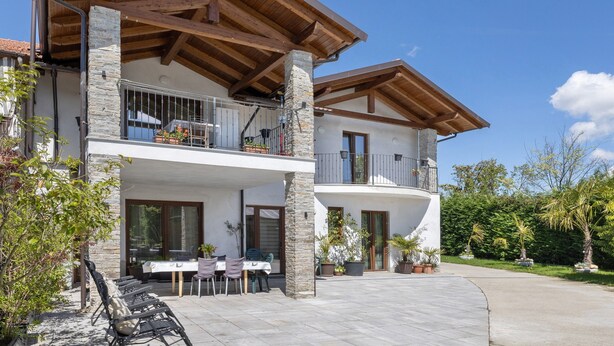 A two-story building with balconies, outdoor seating, and potted plants.