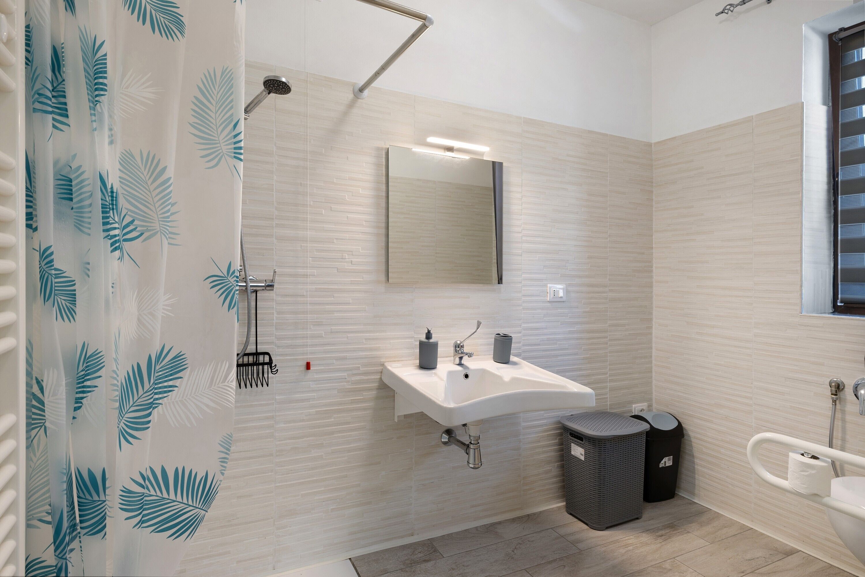 A modern bathroom with a shower, sink, and mirror.